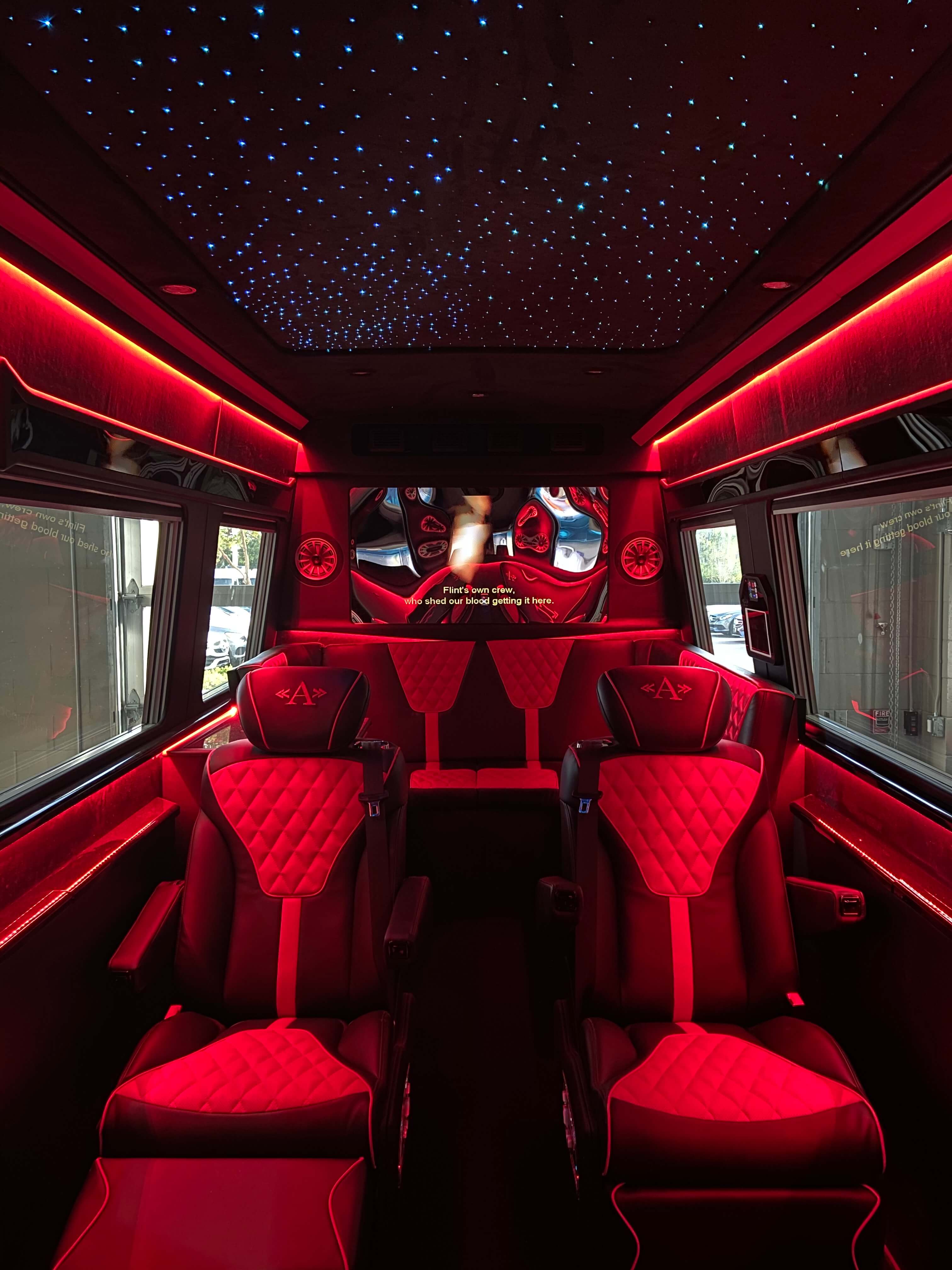 Custom red leather van conversion interior with ambient starlight ceiling and front entertainment display