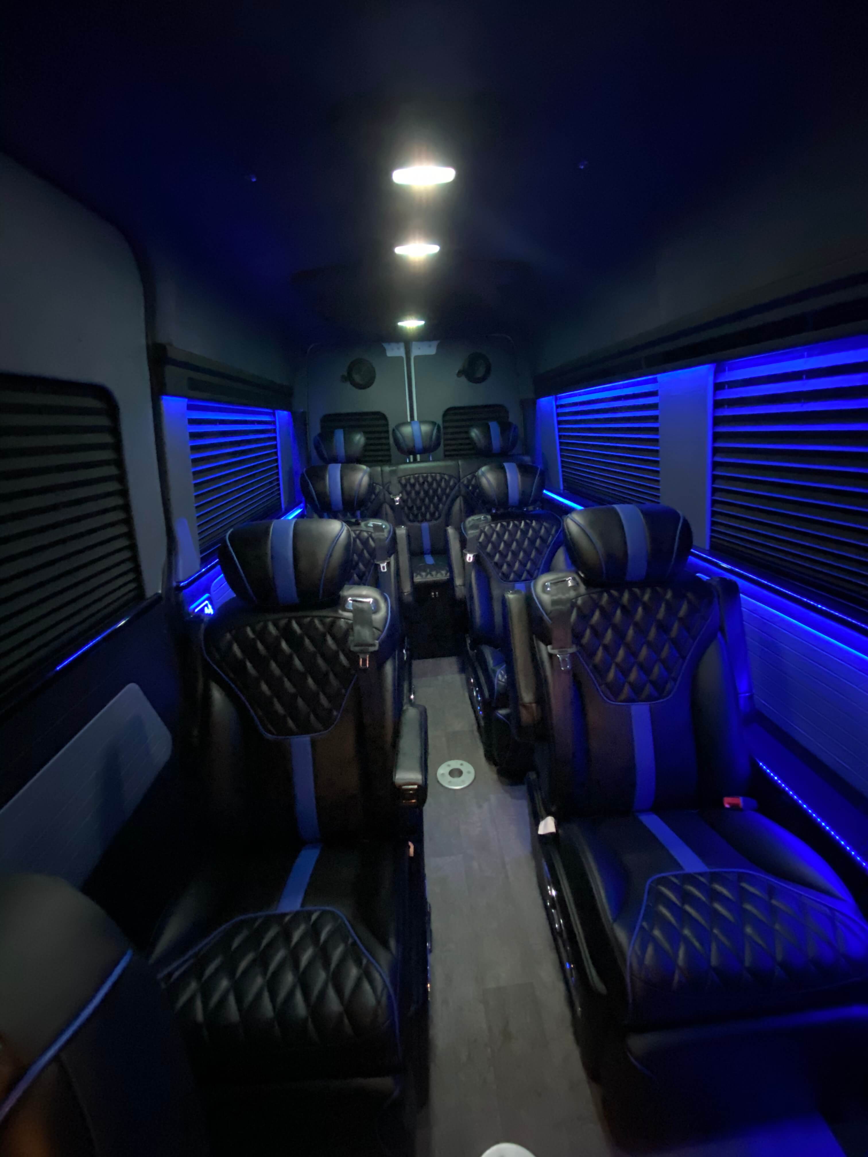 Multi-row black and blue leather van conversion seating with overhead cabin lighting