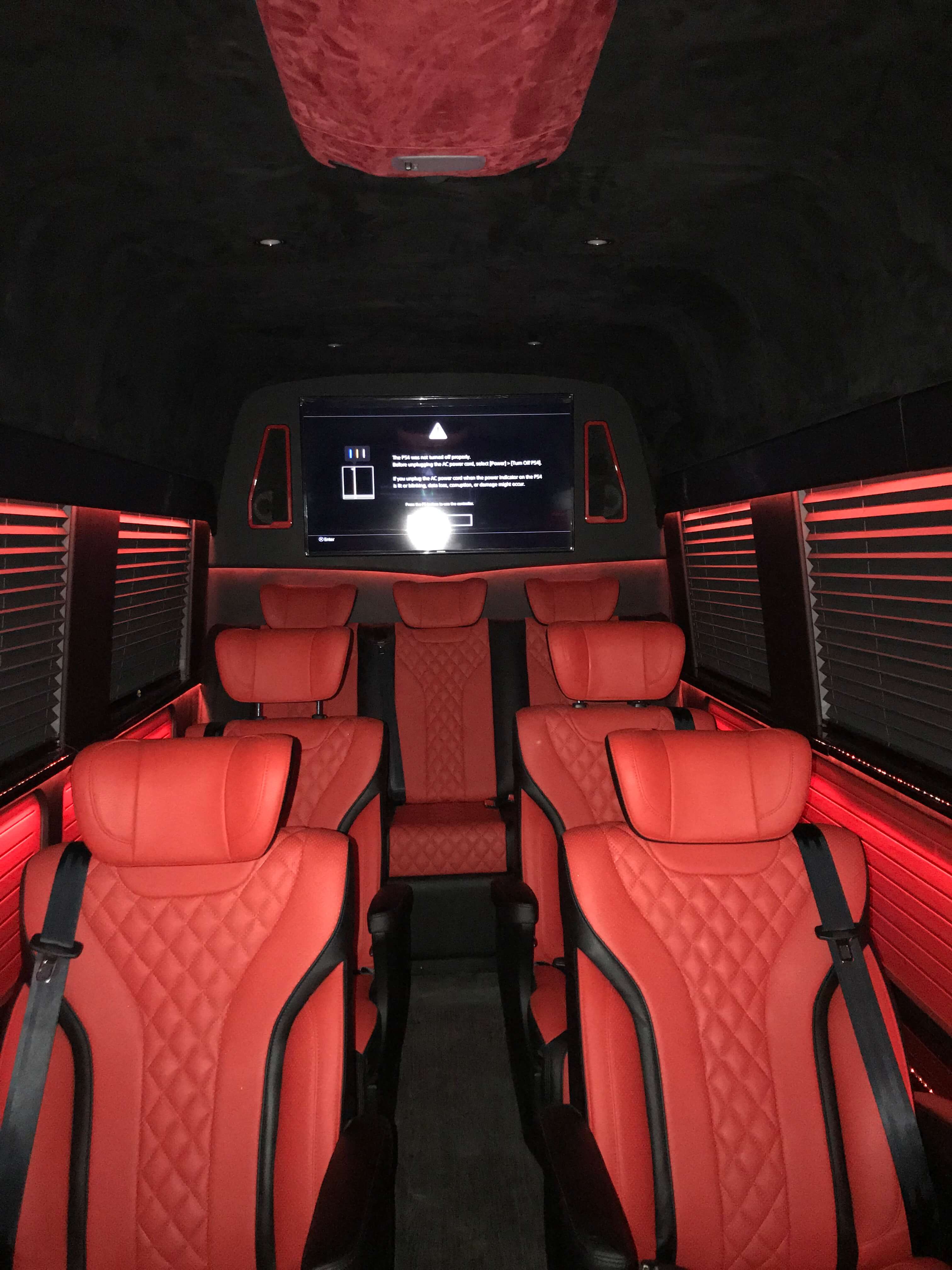 Red leather diamond-quilted van conversion seating with front entertainment display
