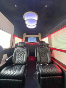 Black diamond-quilted captain chairs with a sculptural dome ceiling light and red accent trim