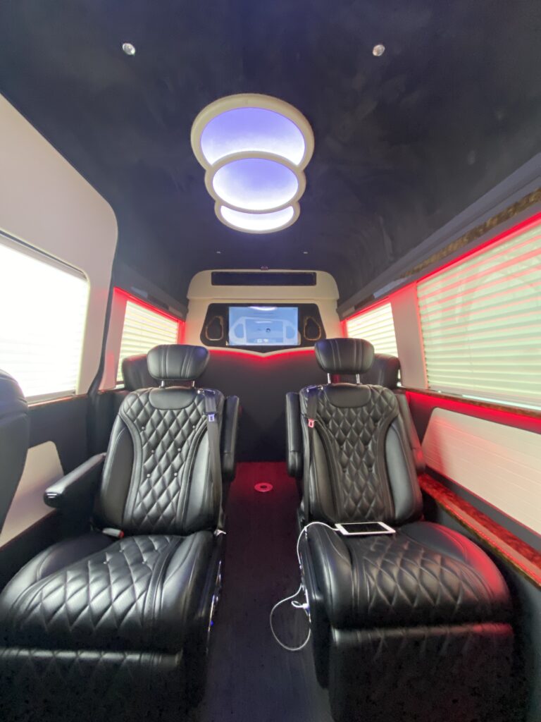 Black diamond-quilted captain chairs with a sculptural dome ceiling light and red accent trim