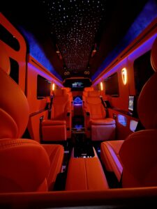 Red leather van conversion interior with multiple entertainment screens and starlight ceiling