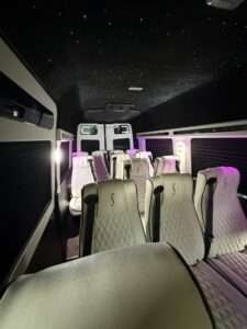 Cream diamond-quilted multi-row van conversion seating with monogrammed headrests and starlight ceiling