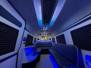 Blue-lit van conversion cabin with captain chairs and overhead entertainment display
