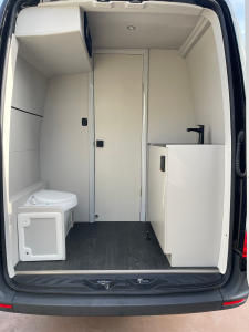Van conversion interior featuring an integrated bathroom compartment and green ambient lighting